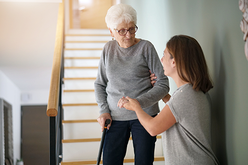 woman helping adult parent down stairs