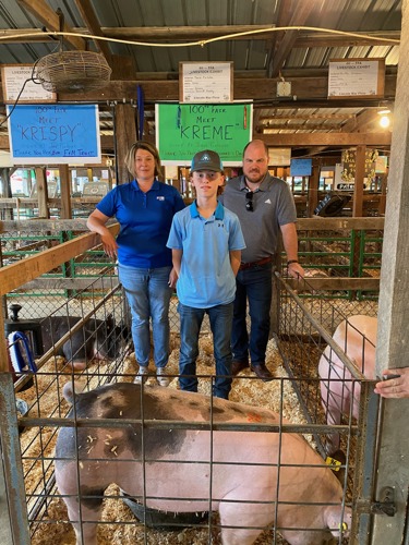 Bank reps standing with Jeron and his pig